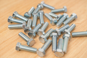 Closeup minimal style of beautiful and clean group of many metal steel silver chrome bolts scatted on wooden background and texture with copy space for text. Minimal hardware concept.