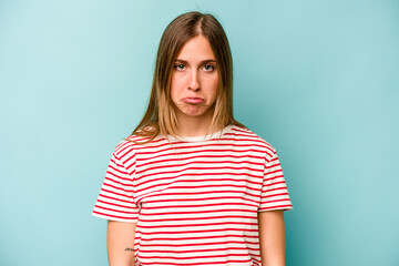 Young caucasian woman isolated on blue background sad, serious face, feeling miserable and displeased.