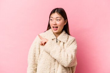 Young Chinese woman isolated on pink background looks aside smiling, cheerful and pleasant.