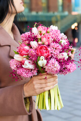 Beautiful young woman holding bridal bouquet in pink lilac tones made of hyacinth, tulips and gypsophila.