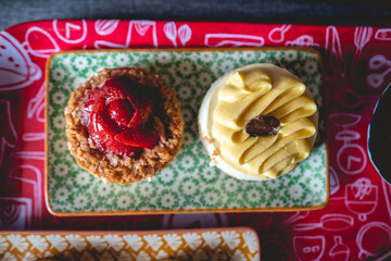Close up of delicious home made breakfast, with colorful tray and plates with pattern with strawberries 'kuchen' cake and passion fruit cheese cake