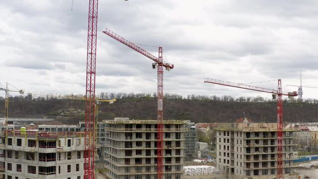Red tower cranes working at construction site in Prague, cloudy day.