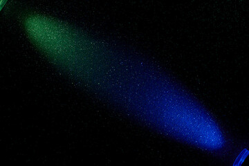 Gradient blue and green beam of light on black grainy background