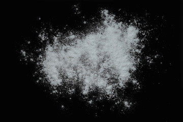 Black background sprinkled with flour, smeared flour, table for cooking, rolling dough. Preparing for baking, top view isolated on a black background or table.