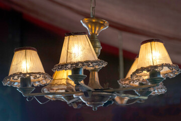 Lustre ancien avec de petits abats jours, suspendu dans un chapiteau.