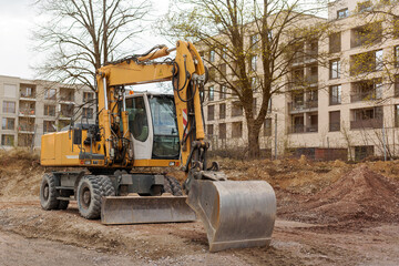 Excavator bulldozer with bucket working on construction site. Wheeled excavator levels land.