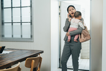 frowning asian woman ceo entering house holding infant is calling her colleague handling trouble at...