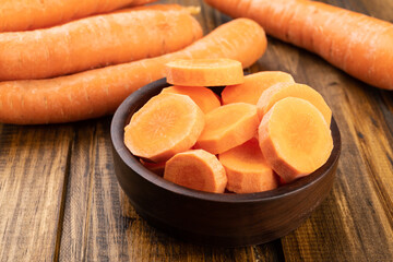 Carrots and slices on a plate over wooden table