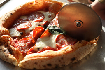 Pizza knife cuts Neapolitan pepperoni pizza