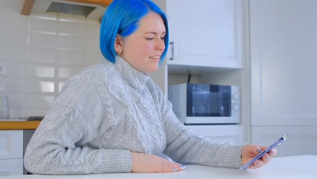 Woman with blye hair using a smartphone. Cheerful female person with dyed hair browsing a mobile phone with a smile