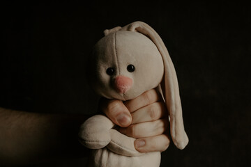Man holds a plush bunny close-up. Abuse, violence or punishment concept