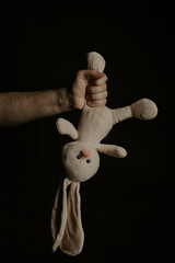 Man holds a plush bunny. Vertical image. Abuse, violence or punishment in family.