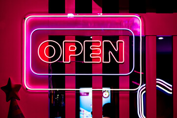 Neon light color blue Open sign on a glass window for business front of shop.