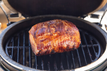 ready to eat - a grilled crispy pork meat from a charcoal grill on the balcony at a sunny spring day