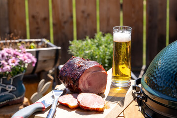 ready to eat - a grilled pork meat on a wood board and a beer on the balcony at a sunny spring day