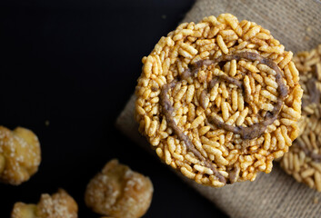 Thai rice cracker or Kaotaen topped with cane sugar on black background. It made of sticky rice. Desert and snack concept.