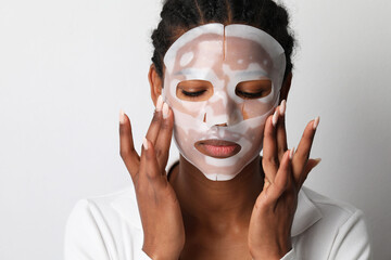 Black woman applies a hydro gel face mask. Skin care and beauty treatments.