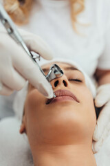 Beautiful brunette getting oxygen face therapy in a beauty salon. Professional skin care treatment.