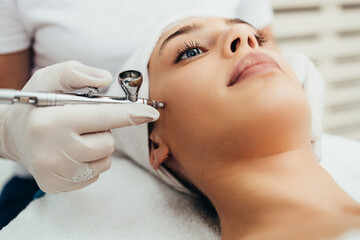 Beautiful brunette getting oxygen face therapy in a beauty salon. Professional skin care treatment.