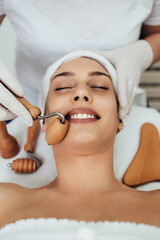 Beautiful brunette getting face maderotherapy in a beauty salon. Professional skin care treatment.