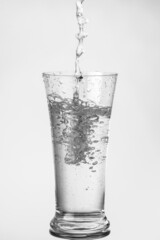 Water is poured into a transparent glass. Black and white image.