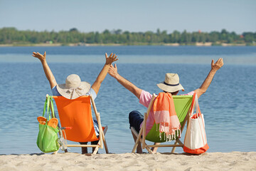 happy elderly couple enjoy their day in deck chairs at the beach