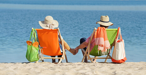 lovely couple relax in deck chairs at the beach