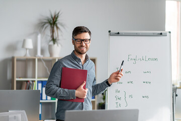 Studying English online. Cheerful mature male teacher giving online foreign language lesson, using...