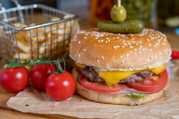 A burger with veal, cheese, lettuce leaves, tomatoes, pickles and hot peppers
