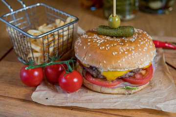 A burger with veal, cheese, lettuce leaves, tomatoes, pickles and hot peppers