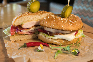 Burger with chicken breast, lettuce leaves, tomatoes, pickles and hot peppers