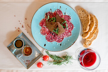 veal carpaccio with black bread slices, olive oil and Dijon mustard