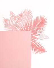 Pastel Pink Tropical Leaves on a White Background. Simple Modern Composition with Paper Cut Palm Tree Leaves, Frame and Butterfies ideal for Card, Banner, Greetings. Top-Down View. No text.