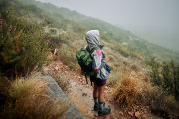 Come rain or sunshine, I always make time for hiking. Shot of a woman wearing her rain jacket while...