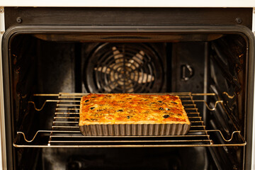 Homemade cheesy Quiche with tomatoes, champignons and olives baked in a home oven. Shallow focus.