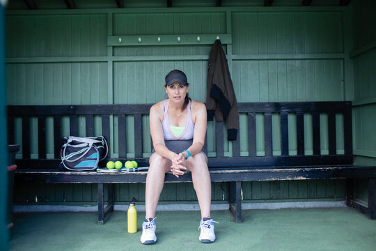 Portrait pregnant woman resting on tennis bench