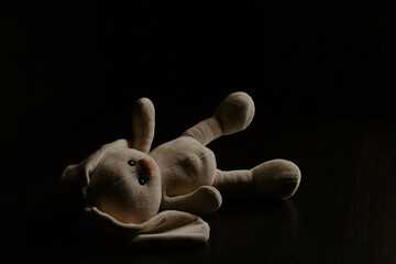 Plush bunny laying down alone at night. Lonely concept, international missing children's day