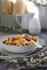 bowl with healthy muesli breakfast on table near spring blossoms branches
