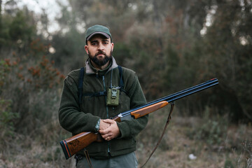 Confident man with rifle in woods during hunting