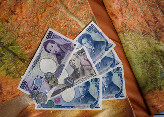 Coins and paper banknotes of Japanese yen on the background of national fabric with embroidery