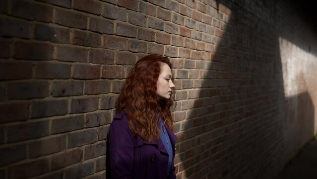Ginger haired girl waiting in an ally way, remembering something funny