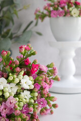 a bouquet of spring flowers on the table against the background of a cup of flowers on a white stand