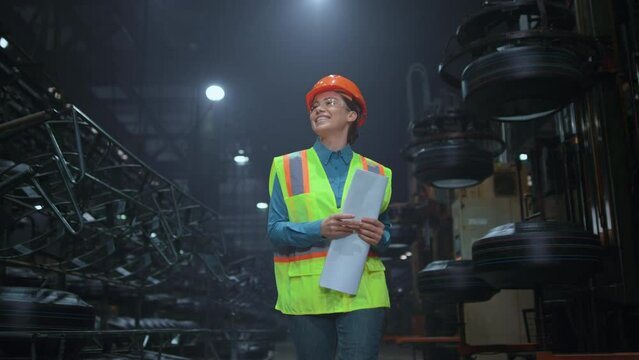 Cheerful woman supervisor walking at digital manufacturing company warehouse.