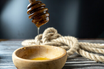 Golden honey on the stick and wooden jar. Aromatic nectar in a bowl.  on wooden background. Honey...