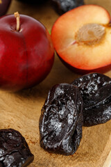 Dried plums or prunes and fresh fruits on teek wooden board background.