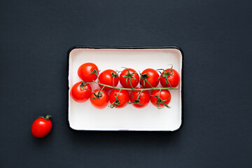Fresh red cherry tomatoes, on a white plate, top view. Creative food design. Minimalist layout.