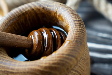 Golden honey on the stick and wooden jar. Aromatic nectar in a bowl.  on wooden background. Honey...