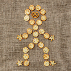 Flat lay human figure made of salty snacks on burlap fabric 