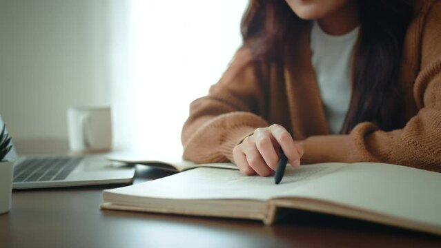 Closeup - Young woman reading book in cozy living room, learning, studying, education, read books, stay home concept.