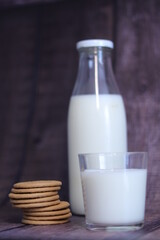 Vaso de leche con galletas  con botella de leche al fondo